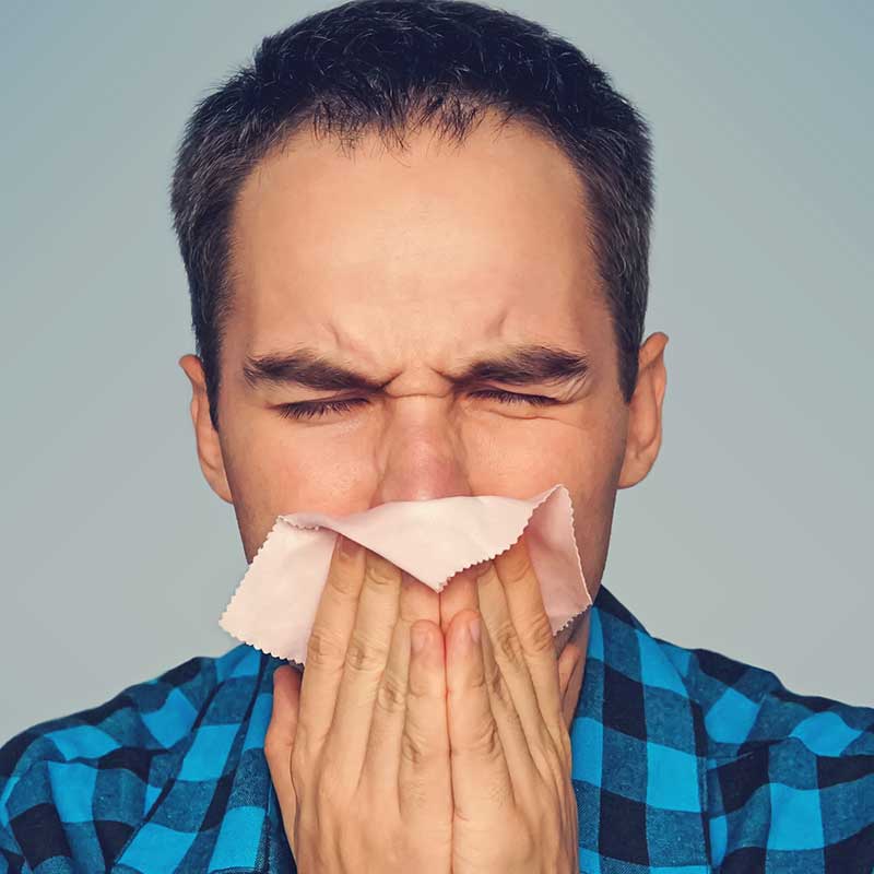 Man blowing nose in attempt to relive his allergies. 